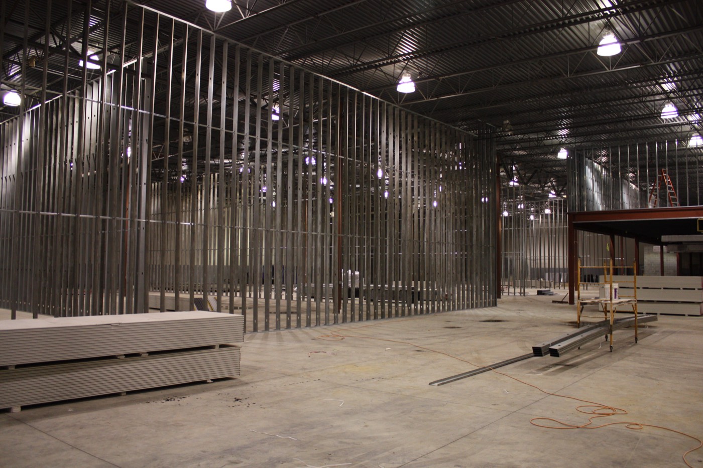 Metal stud framing dividing the interior, stacked drywall waiting on the floor.