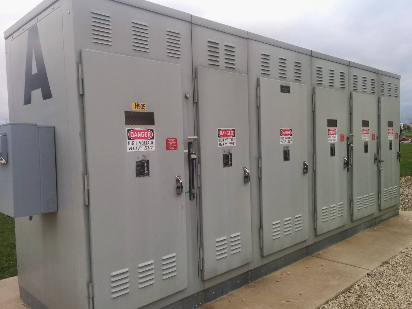 Outdoor medium voltage switchgear lineup with danger high voltage placards.