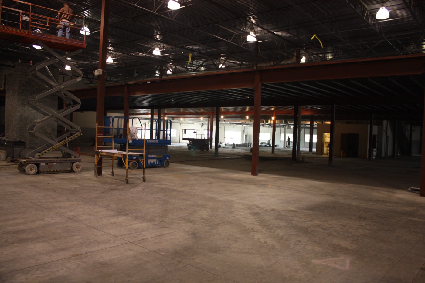 Interior of the building shell during construction, steel structure and mezzanine with scissor lifts on the floor.