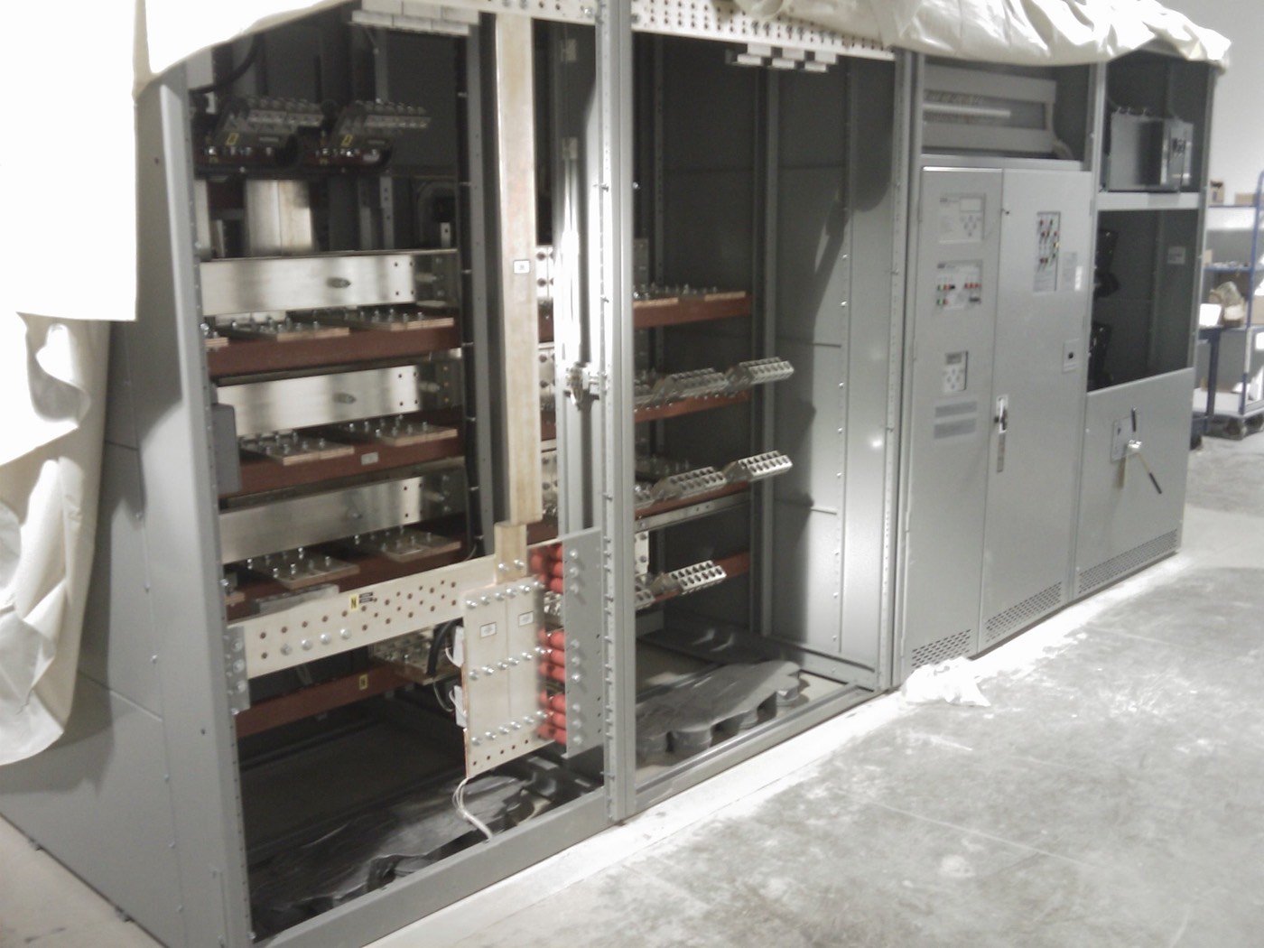 Switchgear lineup during installation, cabinet sections open showing copper busbar and breaker compartments.