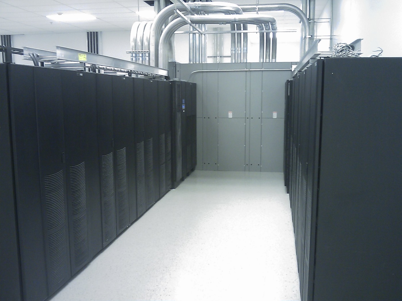 Row of UPS cabinets in a finished electrical room with overhead conduit.